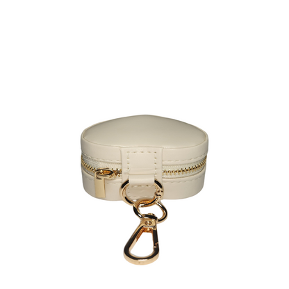 Closed cream heart-shaped jewelry organizer with gold-tone zipper and attached keychain clasp, shown from the side on a white background.